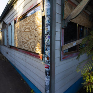 A pipe covered with stickers on the corner of the Maria's Taco Express building