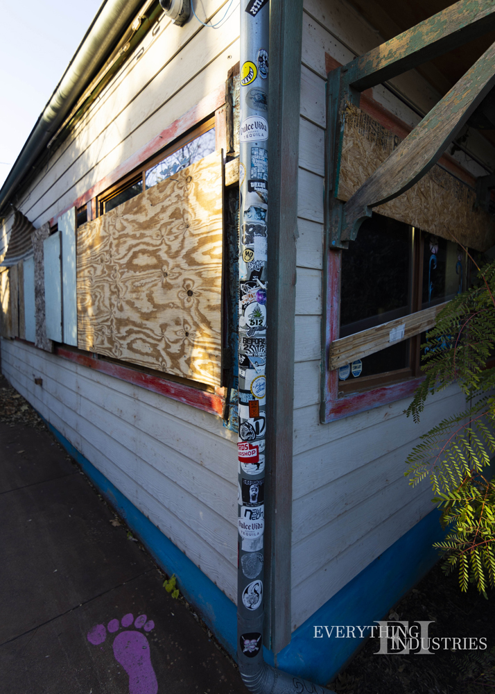 A pipe covered with stickers on the corner of the Maria's Taco Express building