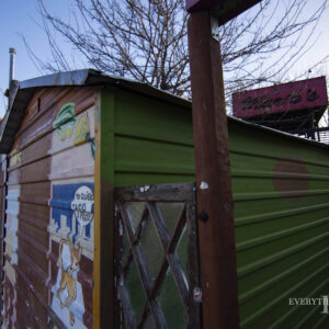 A shed at Maria's Taco Express with art painted on it. Maria's Sign in the background