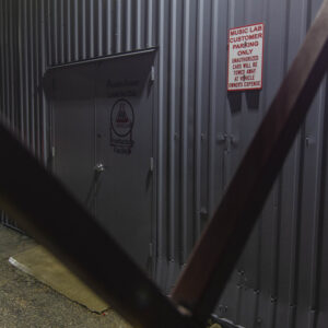 Rear doors to music lab, with a Music Lab parking only sign, crossed iron rails in the foreground