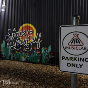 Graffiti reading 'A Space to be Yourself' on a warehouse wall, in the foreground, a Musiclab parking only sign