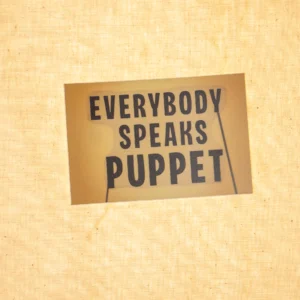 A sticker that reads 'Everybody Speaks Puppet' that is designed to resemble a flat shadow puppet with two rods. It is on backlit muslin.